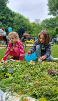 Dwie dziewczynki przycinają kwiatki na polanie w parku