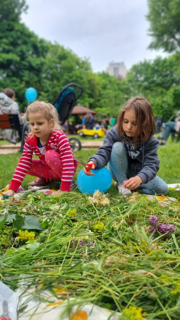 Dwie dziewczynki przycinają kwiatki na polanie w parku